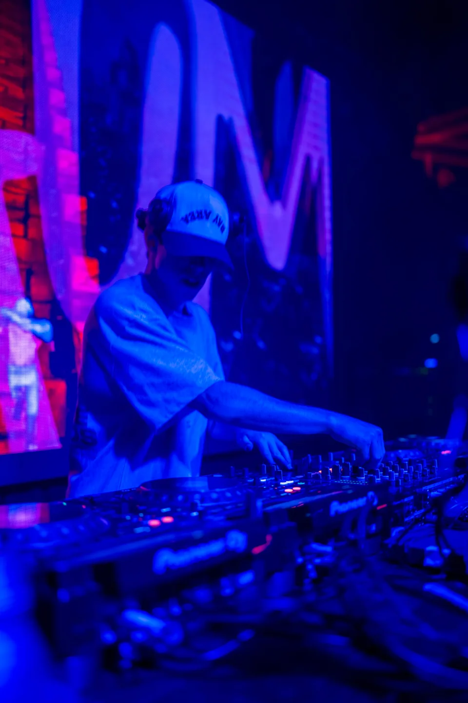 DJ mixing under blue and red club lighting