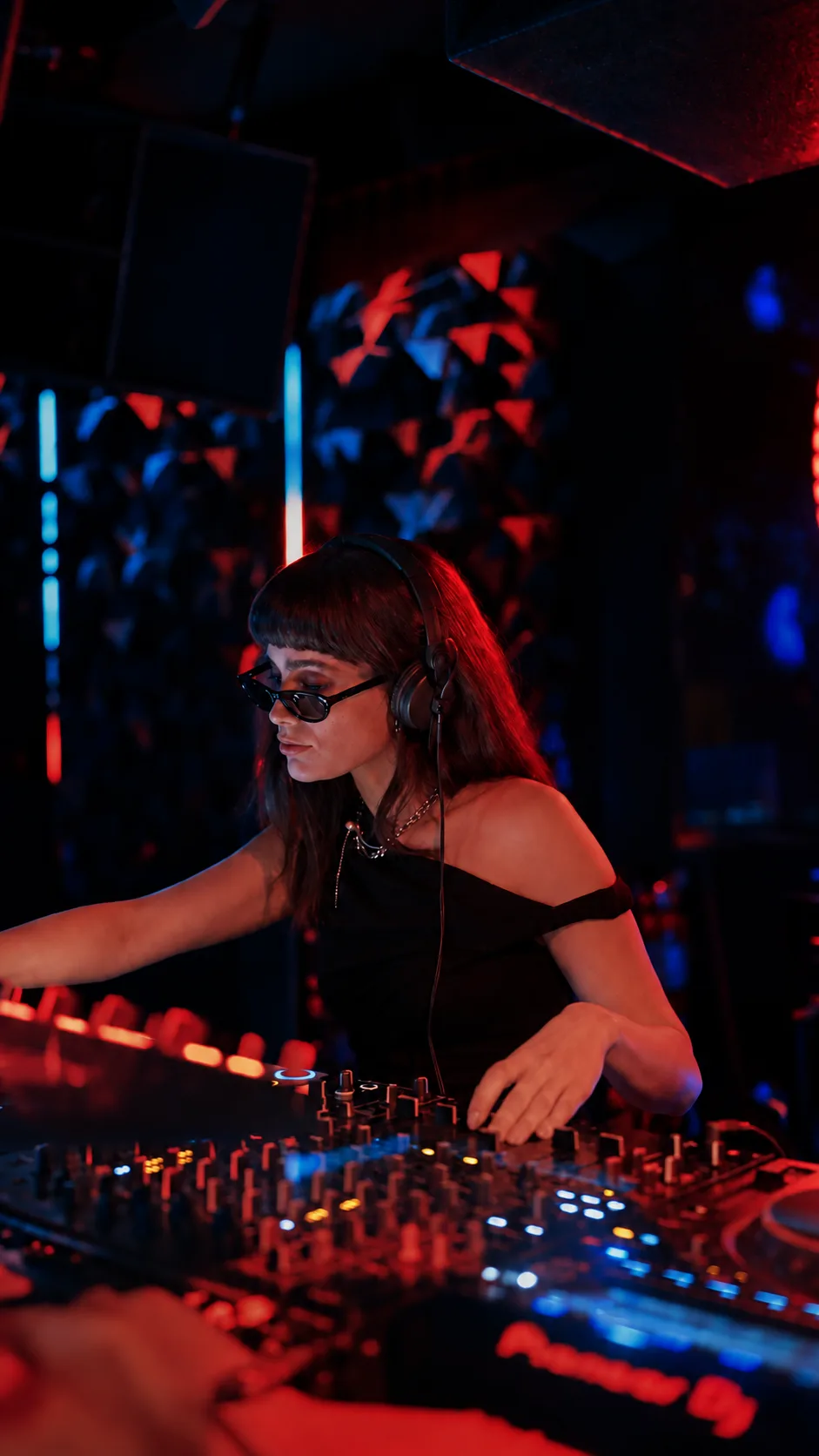 Sara Afshar mixing at the decks under red and blue club lighting